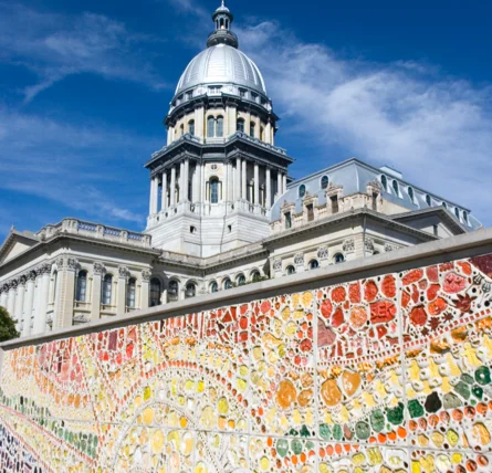 less than 100 characters A colorful mosaic wall with a large, domed building and blue sky in the background